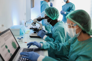 Medical doctor working with microscope and laptop computer inside hospital lab - Focus african man...