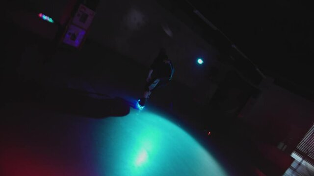 Young guy roller skating professionally in dark studio. Skater on flashing wheels showing tricks on ramp. Example of underground street culture. Concept of extreme, youth, lifestyle, nightlife.
