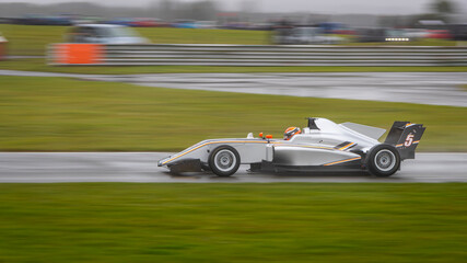 A panning shot of a racing car as it circuits a track.
