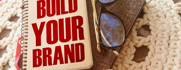 Build Your Brand words on copybook. Pen, glasses. Marketing business concept.