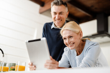 Fototapeta na wymiar Smiling mid aged couple on a video call via digital tablet