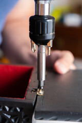 Close-up of a man screwing a hinge into a wooden box. Concept carpentry at home, furniture restoration