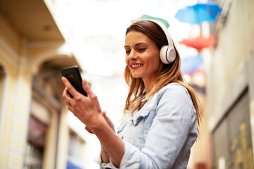 Young smiling woman with headphones outdoors. Beautiful woman listening the music