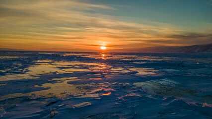 Magnificent sunset over frozen Lake Baikal.  Frozen pieces of ice on the lake surface. Irkutsk region, Russia