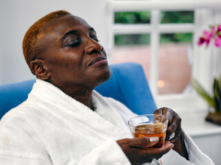 Mature woman in white bathrobe enjoying tea