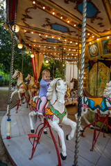 Cute baby girl on the horse of old retro carousel, Prague, Czech republic 