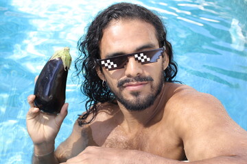 Hilarious man holding an eggplant in swimming pool