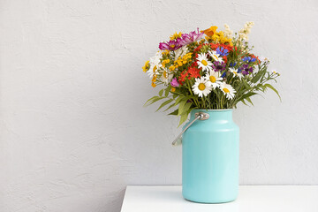 Bouquet of bright flowers in tin can vase on background grey stone wall. Template for postcard....