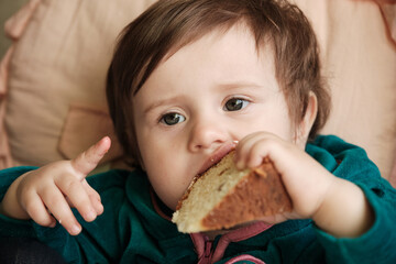 1 year old baby old baby girl eats Panettone. Cute little caucasian girl holding Easter cake.