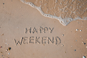 Phrase Happy weekend written on sand at beach, top view