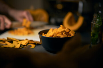 Man cuts a cool round pumpkin into small pieces with a dark background. The dark style with dim...
