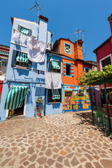 Burano island, houses with bright colors and clothes hanging on clotheslines to dry in the sun. House of Bepi, Venetian lagoon, Venice, UNESCO world heritage site, Veneto, Italy, Europe.