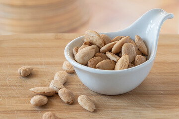 Almonds in ceramic bowl on oak wood table.