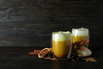 Glasses of pumpkin latte and ingredients on rustic wooden background