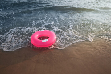 Bright pink inflatable ring on sandy beach near sea, space for text