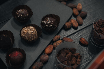 Handmade Chocolate raw candies on dark wooden rustic background with cacao beans. Dark milk chocolates set