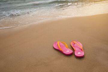 Fototapeta na wymiar Bright pink beach slippers on sand near sea, space for text