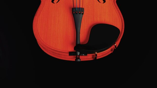 Violin on a dark background. Motion along the instrument with a dolly camera with a beautiful transition from black to black. Video to advertise violin courses, a musical instrument store or workshop.