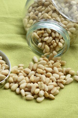 a pot from which pine nuts come. it lies on a green background. pine nuts are high in unsaturated fats. Omega 3 fatty acids are the most in the pine nuts.