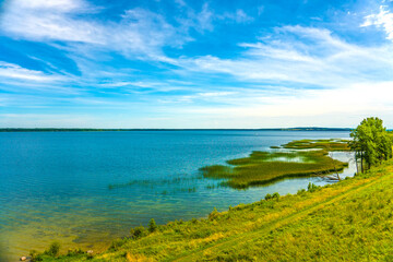 Scenery with blooming wild flowers on the hill near the big beautiful lake