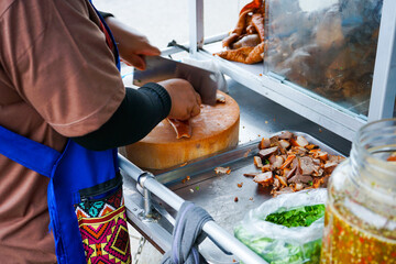 Delicious stewed ear pork at the street food. Motion blurred hand of seller chops the pork on cutting board.