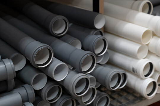 Stack of PVC canalization pipes plumbing tube on a hardware store stock. Gray plastic pipes. Industrial for plumber. Construction Materials, selective focus