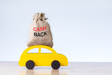 Cash back or money refund concept. Yellow toy car with money bag on grey background with place for...