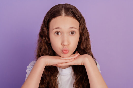 Photo of pretty girl hands on chin sending air kiss isolated over purple background