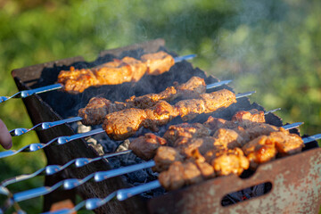 A lot of juicy meat kebabs in a row on the grill. Meat pieces strung on metal skewers on the grill at sunset. The process of cooking kebabs with a lot of smoke. Cooking in nature