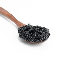 fresh grainy black paddlefish caviar in brown wooden spoon on white background, close up