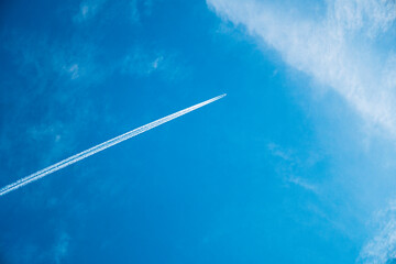 Airplane flying in the blue sky among clouds and sunlight
 - Powered by Adobe