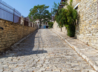 a beautiful street of the old city, a wall paved with light stone, a road, a sidewalk, everything for people's life
