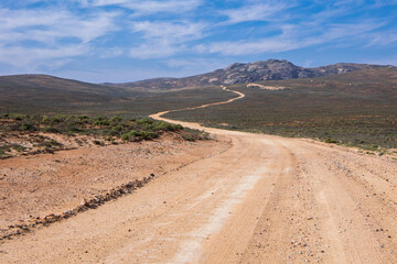 A long dirt road leading into the mountains in the distance