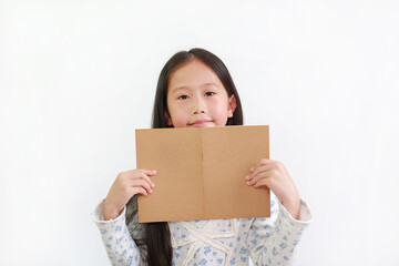 Happy Asian little girl child holding open brown book with looking at camera over white studio background