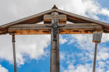 Wooden crucifixion of Jesus Christ on a background of blue sky with clouds.