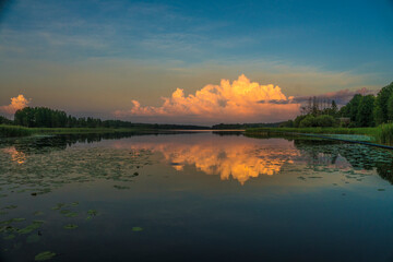 Dramatic clouds lit by the sun at sunset and reflection in the water of the Lake