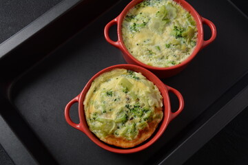 Healthy snack Broccoli  with eggs cheddar cheese and thyme close-up in mini casserole .