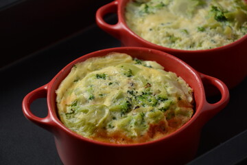 Healthy snack Broccoli  with eggs cheddar cheese and thyme close-up in mini casserole .