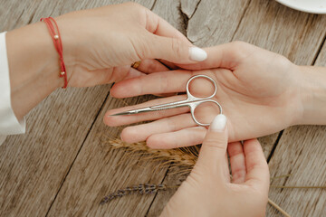 Hand with manicure scissors on wooden table