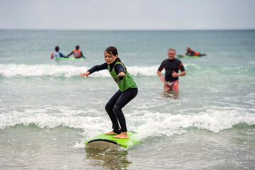 cute young girl learning to surf with her daddy