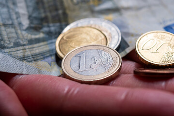 Euro coins and bills in hands, extreme close-up view