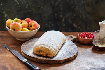 Strudel with apples and cranberries. Icing sugar, coffee, berries. Wooden background, side view. 