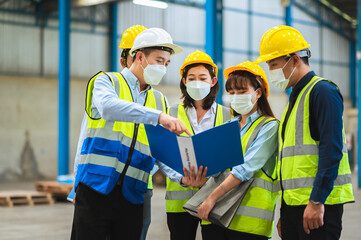 The factory employee consists of engineers, foreman, technicians, and related department staff. Wear a mask, hard hat, and vest. meeting before starting work inside the warehouse. Teamwork concept.