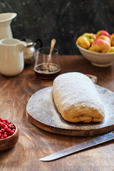 Strudel with apples and cranberries. Icing sugar, coffee, berries. Wooden background, side view. 