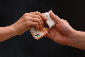 Drug dealer passes a dose to a merchant, sachets of powder on a black background.