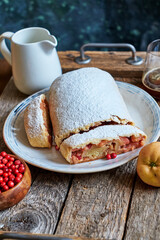 Strudel with apples and cranberries. Icing sugar, coffee, berries. Wooden background, side view. 