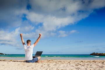 Happy exited man with raised hands up celebrate success in job or great news in front of laptop