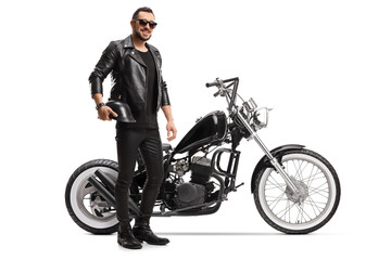 Obraz na płótnie Canvas Full length portrait of a biker with a chopper holding helmet and wearing sunglasses