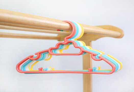 Colored plastic Clothes Hangers on wooden clothes line against white background