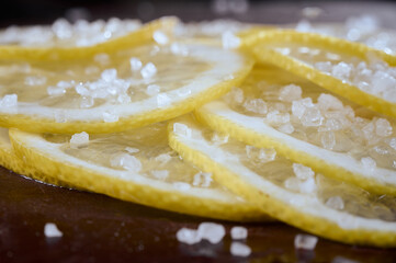 Lemon slices sprinkled with salt close-up on a dark background. Appetizer for cocktails.